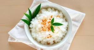 Coconut rice in rice cooker served in a white bowl with toasted coconut flakes on top, Served bowl with coconut flakes